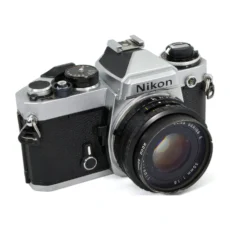 Appareil photo reflex argentique Nikon FE de face avec objectif 50mm f/1.8 et filtre cabossé