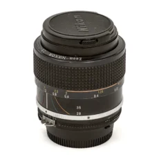 Objectif photo vintage Nikon Zoom-Nikkor 28-50mm f/3.5 AI-S posé debout avec son bouchon avant