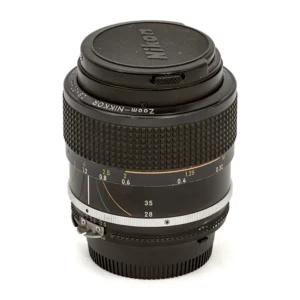 Objectif photo vintage Nikon Zoom-Nikkor 28-50mm f/3.5 AI-S posé debout avec son bouchon avant