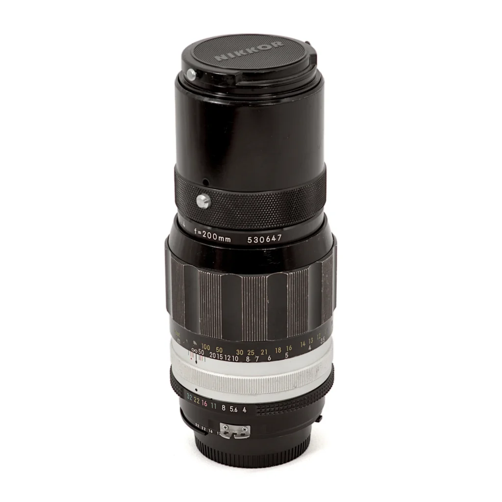 Objectif Nikon Nikkor 200mm f/4 Non-AI debout avec son bouchon avant