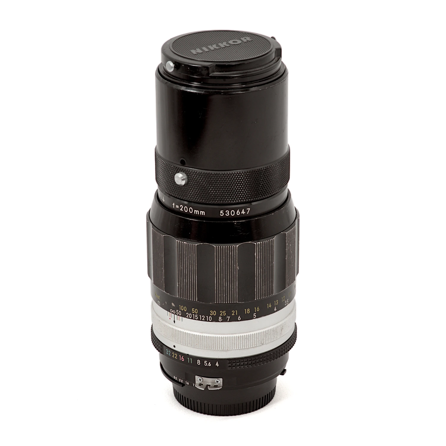 Objectif Nikon Nikkor 200mm f/4 Non-AI debout avec son bouchon avant