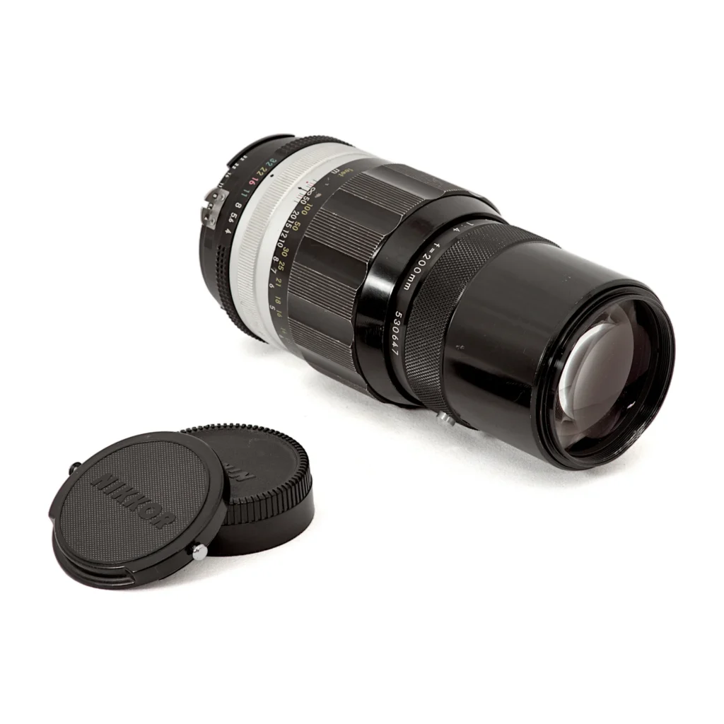 Objectif Nikon Nikkor 200mm f/4 couché montrant la lentille frontale et les bouchons