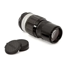 Objectif Nikon Nikkor 200mm f/4 couché montrant la lentille frontale et les bouchons