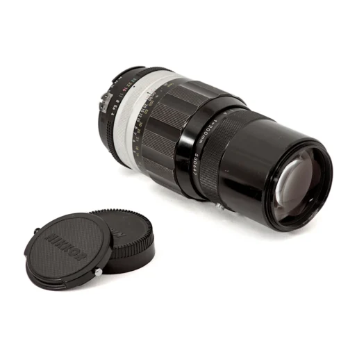 Objectif Nikon Nikkor 200mm f/4 couché montrant la lentille frontale et les bouchons