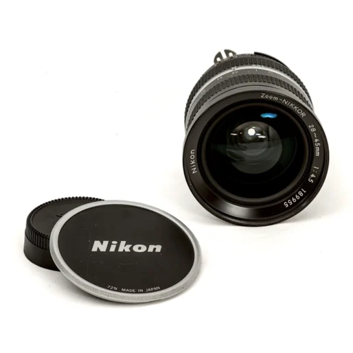 Lentille frontale de l'objectif Nikon 28-45mm avec son bouchon d'origine posé à côté