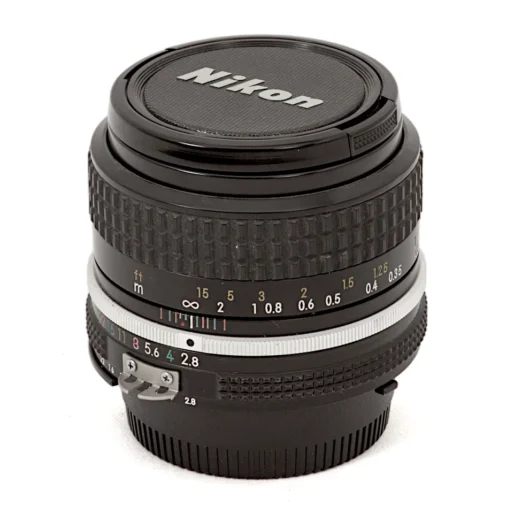 Objectif Nikon NIKKOR 35mm f/2.8 AI vu de face avec son bouchon d'origine