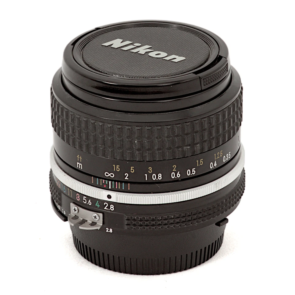 Objectif Nikon NIKKOR 35mm f/2.8 AI vu de face avec son bouchon d