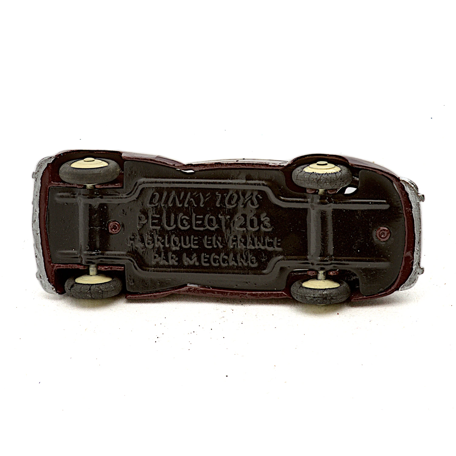 Gros plan sur le châssis de la Dinky Toys Peugeot 203 avec les inscriptions Meccano