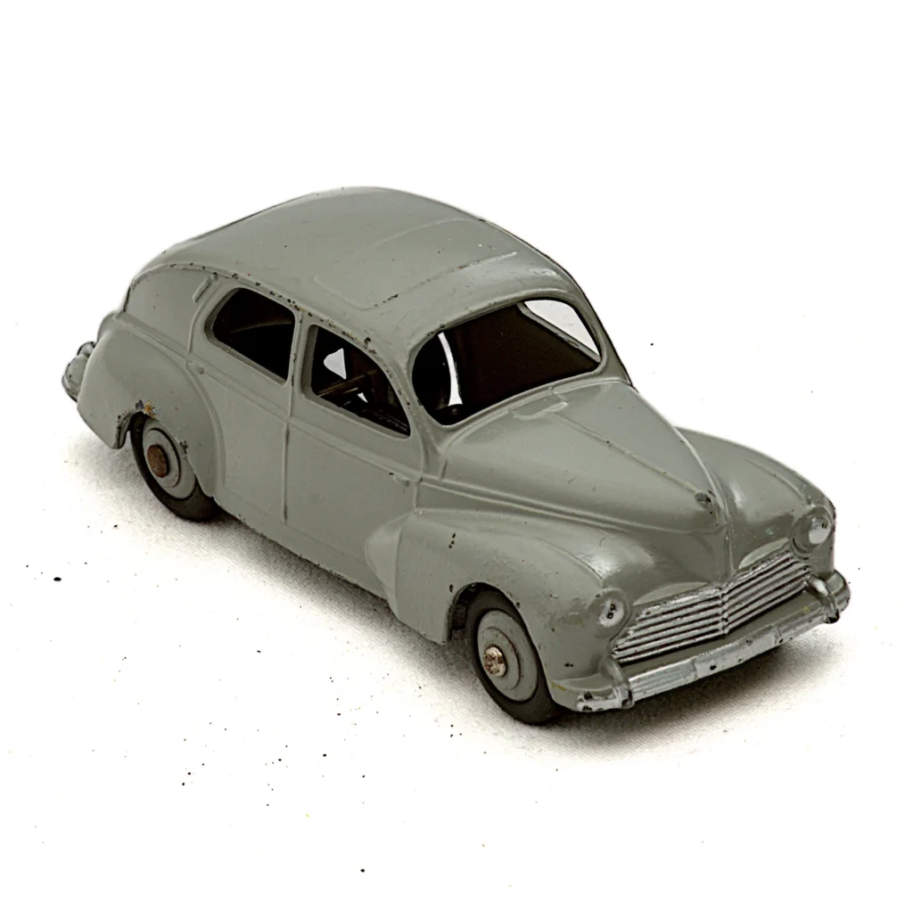 Vue de trois quarts avant de la miniature Dinky Toys Peugeot 203 grise avec éclats de peinture