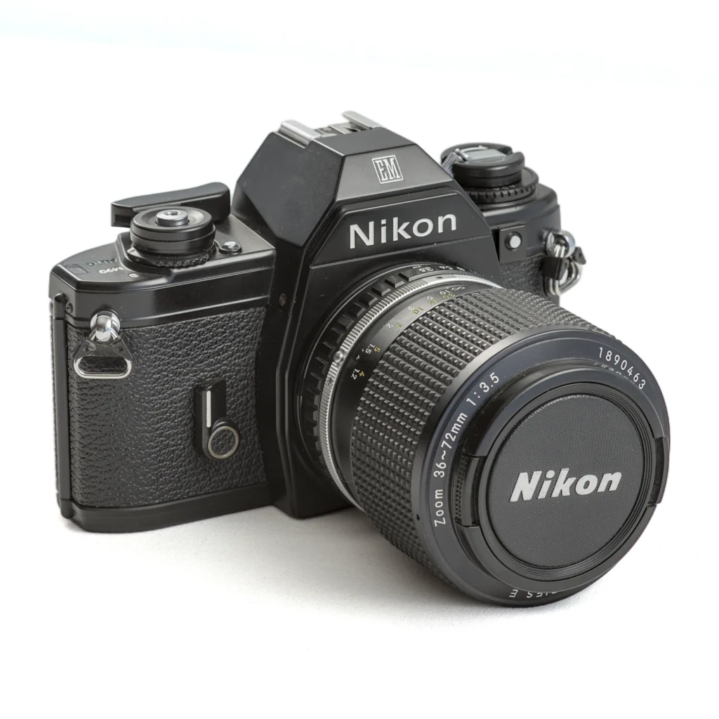 Appareil photo reflex argentique Nikon EM de trois-quarts avec objectif