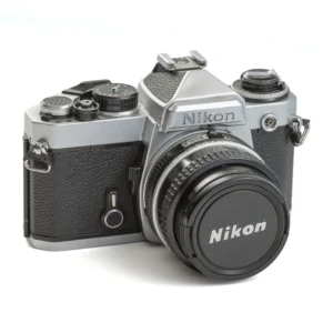 Appareil photo reflex Nikon FE argentique de face avec son bouchon d'objectif