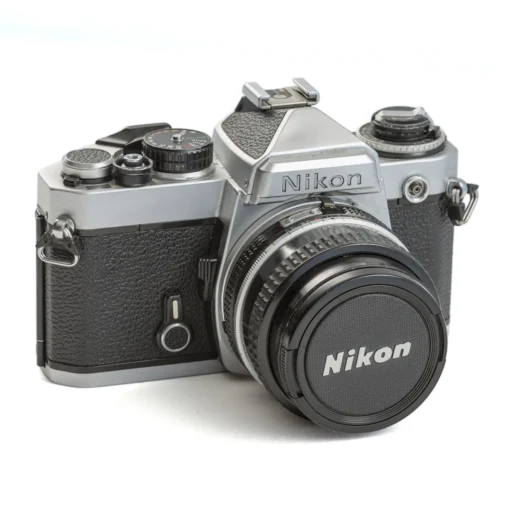 Appareil photo reflex Nikon FE argentique de face avec son bouchon d'objectif