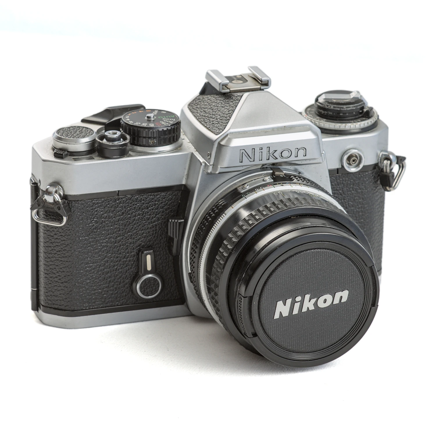 Appareil photo reflex Nikon FE argentique de face avec son bouchon d