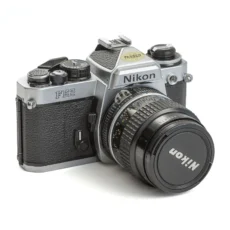 Appareil photo reflex argentique Nikon FE2 de trois quarts face avec son objectif