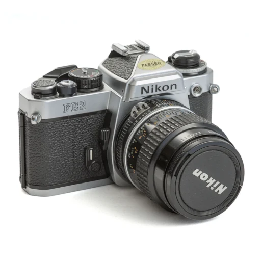 Appareil photo reflex argentique Nikon FE2 de trois quarts face avec son objectif