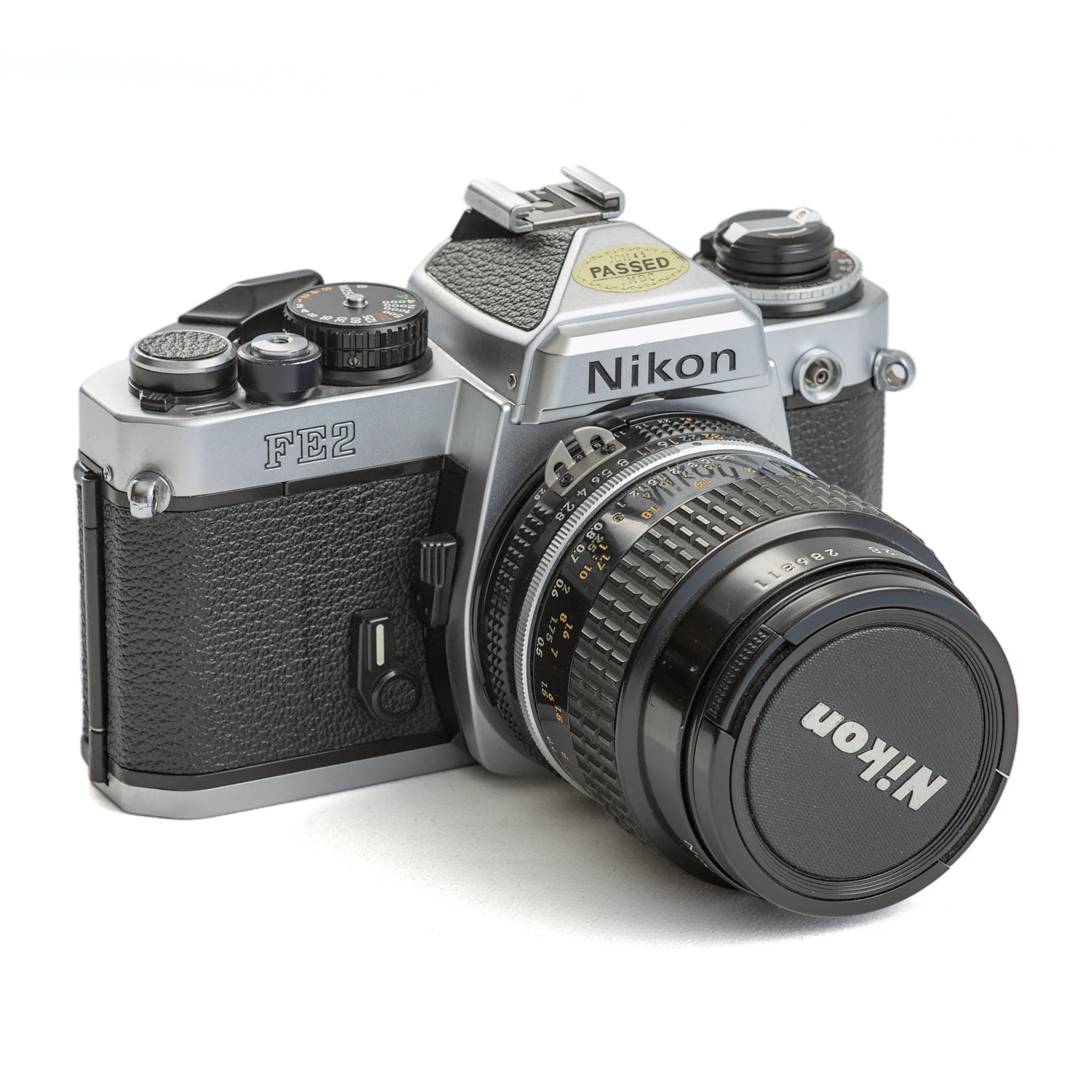 Appareil photo reflex argentique Nikon FE2 de trois quarts face avec son objectif