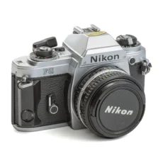 Appareil photo reflex argentique Nikon FG de face avec son bouchon d'objectif