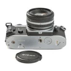Vue de dessous de l'appareil photo Nikon FG avec le bouchon d'objectif posé à côté