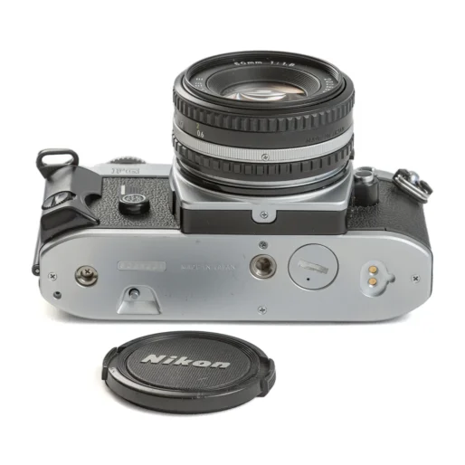 Vue de dessous de l'appareil photo Nikon FG avec le bouchon d'objectif posé à côté