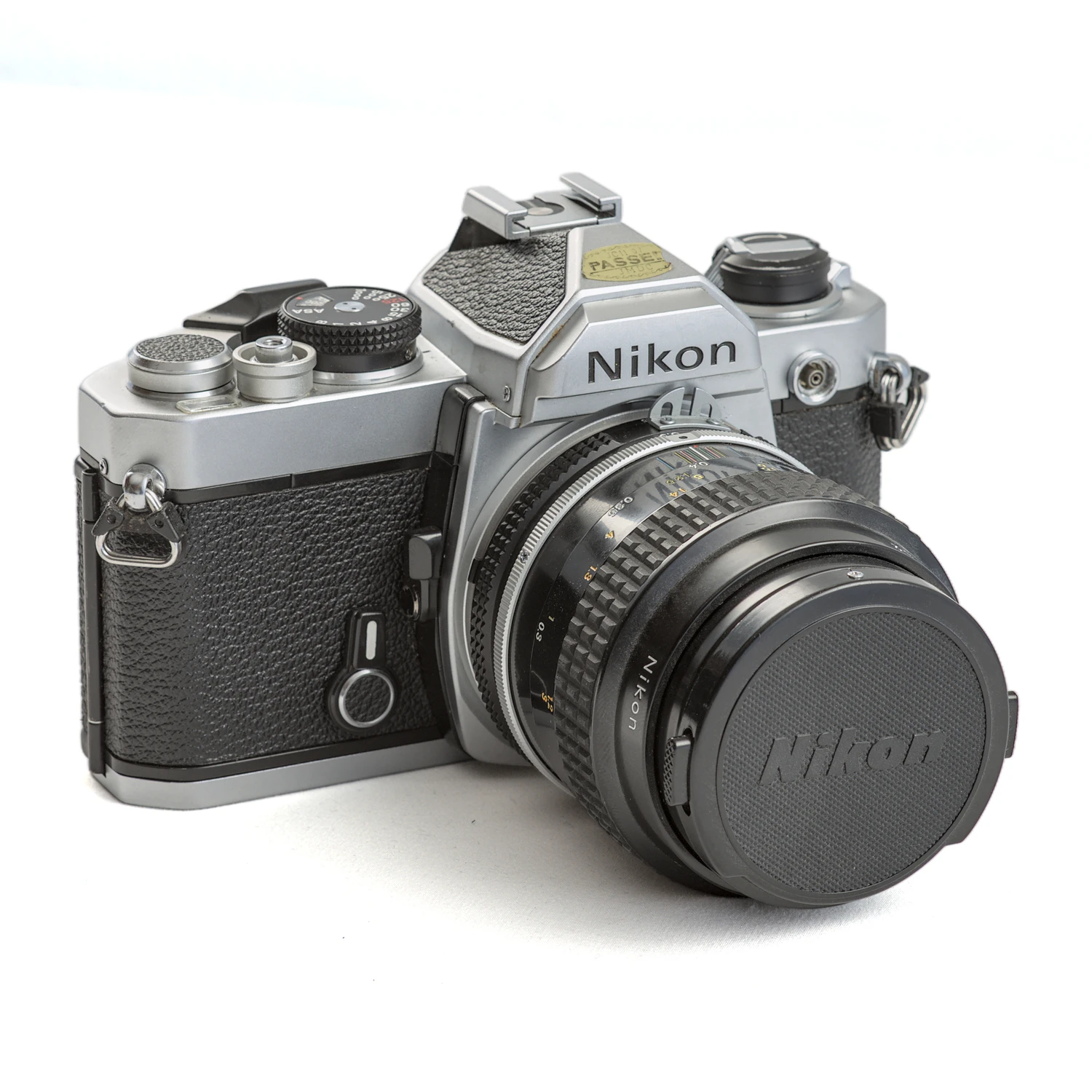 Appareil photo reflex argentique Nikon FM de trois-quarts avec objectif Micro-Nikkor